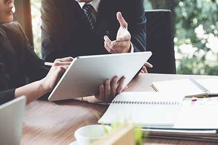 Business Woman and Lawyer Discussing a Legal Matter and Using Digital Tablet on Wooden Desk in Office