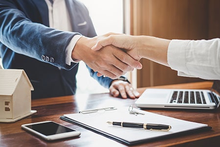 Real Estate Agent and Customers Shaking Hands Together Celebrating Finished Contract About Home Insurance and Investment Loan